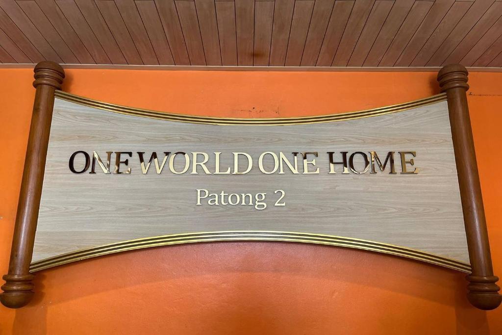 a one world one home sign hanging on a wall at One World One Home Patong 2 in Patong Beach