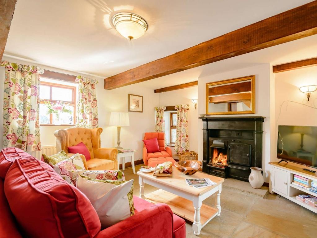 a living room with red furniture and a fireplace at 2 bed in Ramsgill 89165 in Bouthwaite