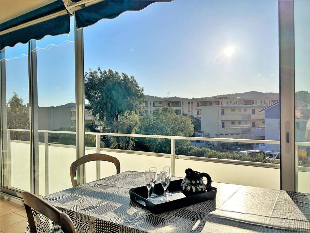 - une table avec des verres à vin sur le balcon dans l'établissement Appartement à 150m de la plage avec terrasse fermée et parking privatif - Bormes-les-Mimosas - FR-1-251-578, à Bormes-les-Mimosas