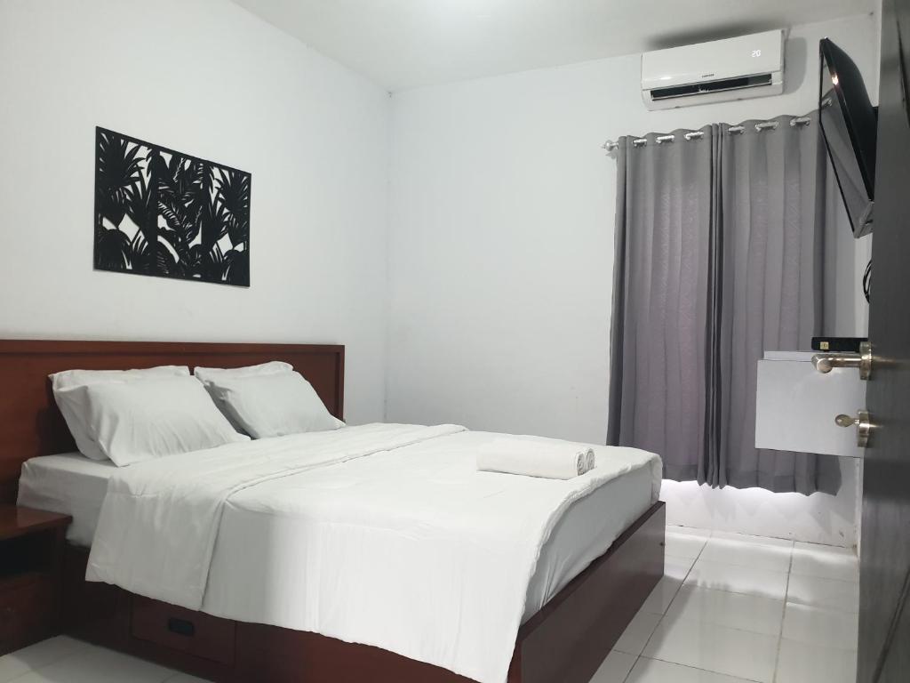Un dormitorio con una gran cama blanca y una ventana en BTN Mahkota Pemenang 13 Tamarin 3A en Pawenang