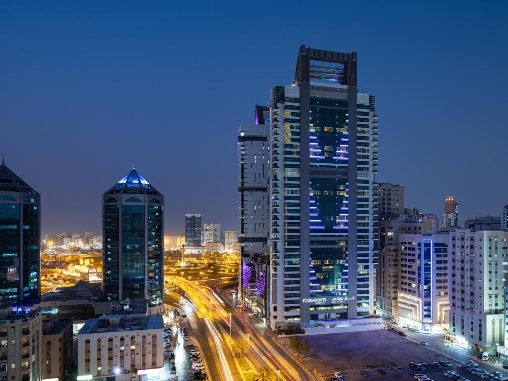 een skyline van de stad met 's nachts hoge gebouwen bij Four Points by Sheraton Sharjah in Sharjah