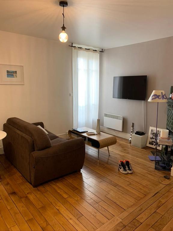 a living room with a couch and a flat screen tv at Appartement Paris Ouest Chambre in Levallois-Perret