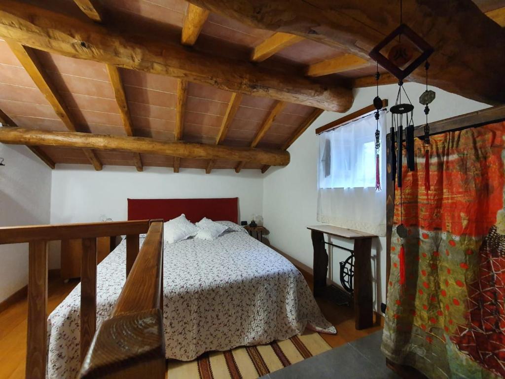 1 dormitorio con 1 cama en una habitación con techos de madera en La casina rossa della fornace, en Cutigliano