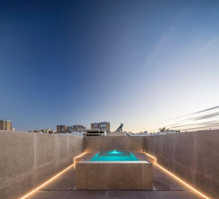 einen Swimmingpool auf dem Dach eines Gebäudes mit Beleuchtung in der Unterkunft Espectacular casa de lujo y diseño- Sevillarooms in Sevilla