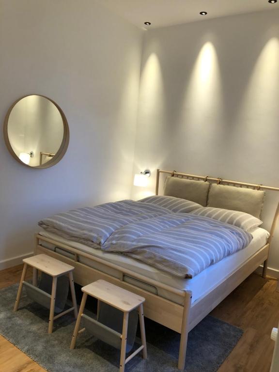 1 dormitorio con 1 cama con espejo y 2 taburetes en Seehus 8, en Norderney