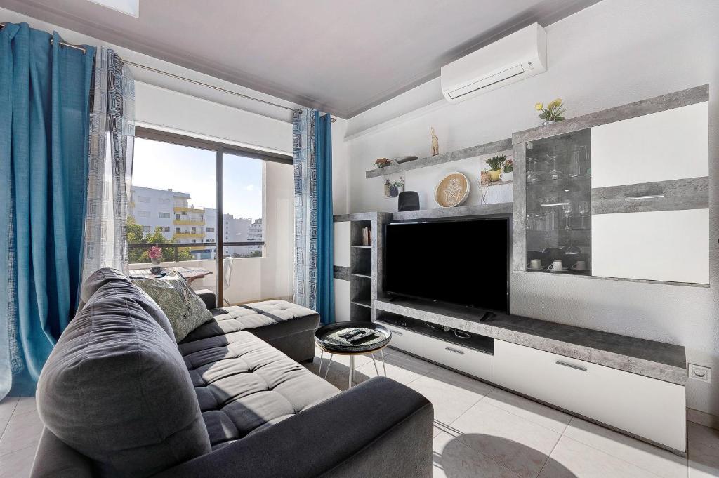 a living room with a couch and a large television at Refúgio Praia da Rocha in Portimão