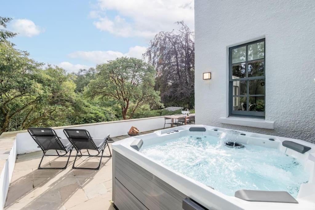 a jacuzzi tub on a balcony with chairs at Stunning Dalchenna w/hot tub & huge garden in Stirling