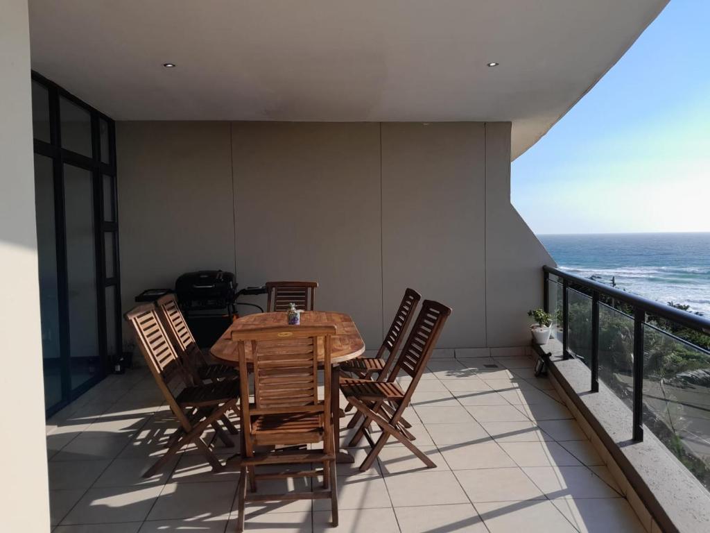 a table and chairs on a balcony with the ocean at CoRAL REEF 207 in La Mercy
