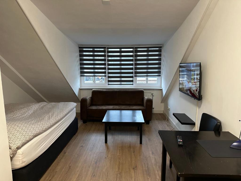 1 dormitorio con cama, sofá y mesa en B&B Santorini, en Maasbree