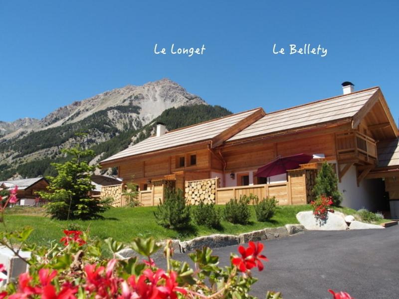 a large wooden building with a mountain in the background at Le Longet in Névache