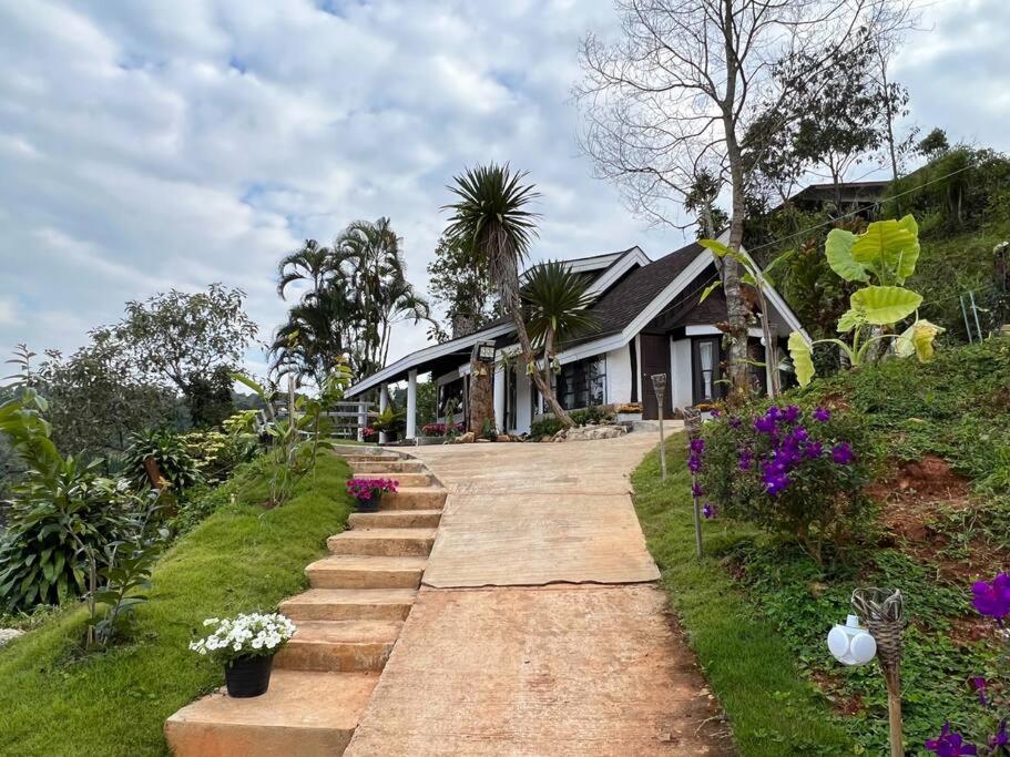 uma casa com um caminho que leva a uma casa com flores em Baan Khun Waew Rimdoi Super Cozy Guesthouse em Chiang Mai