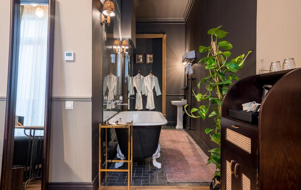 La salle de bains est pourvue d'une grande baignoire et d'une plante. dans l'établissement Communal Hotel Kutaisi, à Koutaïssi