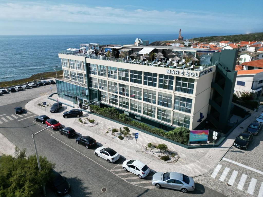 un gran edificio con coches estacionados en un estacionamiento en Hotel Mar e Sol & Spa en São Pedro de Moel