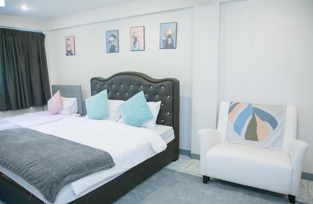 1 dormitorio con 1 cama y 1 silla blanca en OYO 75457 Hello Host en Chiang Mai