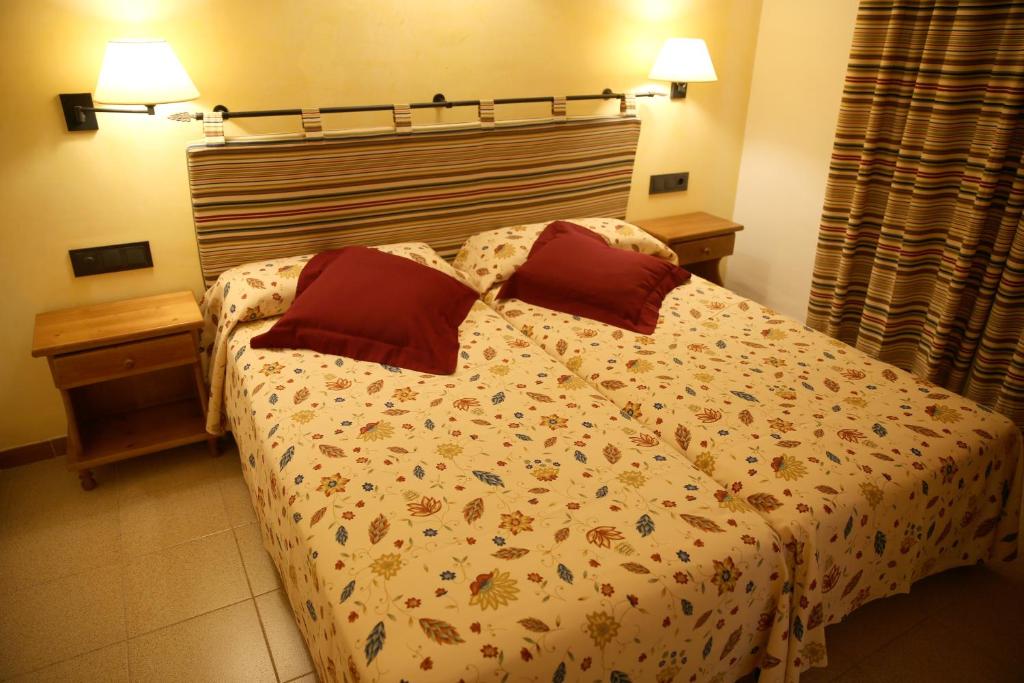a bedroom with a bed with two red pillows at Apartamentos Mar y Sal in La Savina