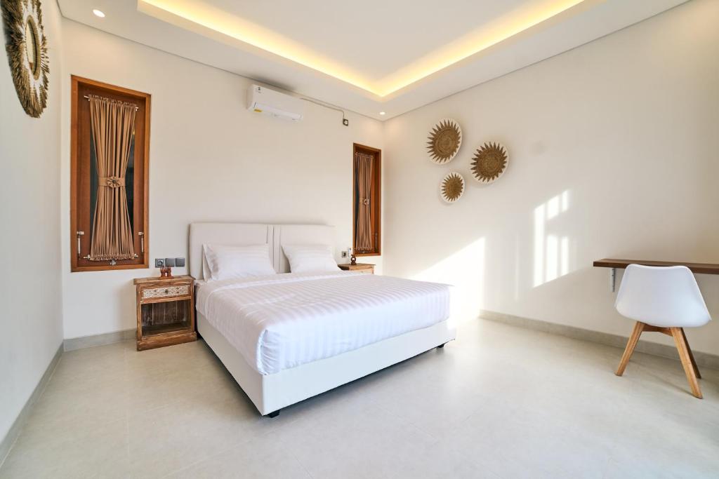 ein weißes Schlafzimmer mit einem weißen Bett und einem Schreibtisch in der Unterkunft Diana ArtVilla by ArthouseBali in Canggu