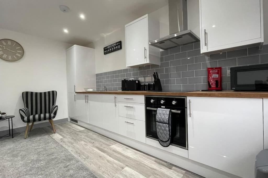 a kitchen with white cabinets and a black dishwasher at 202 Grosvenor House - Wakefield in Wakefield