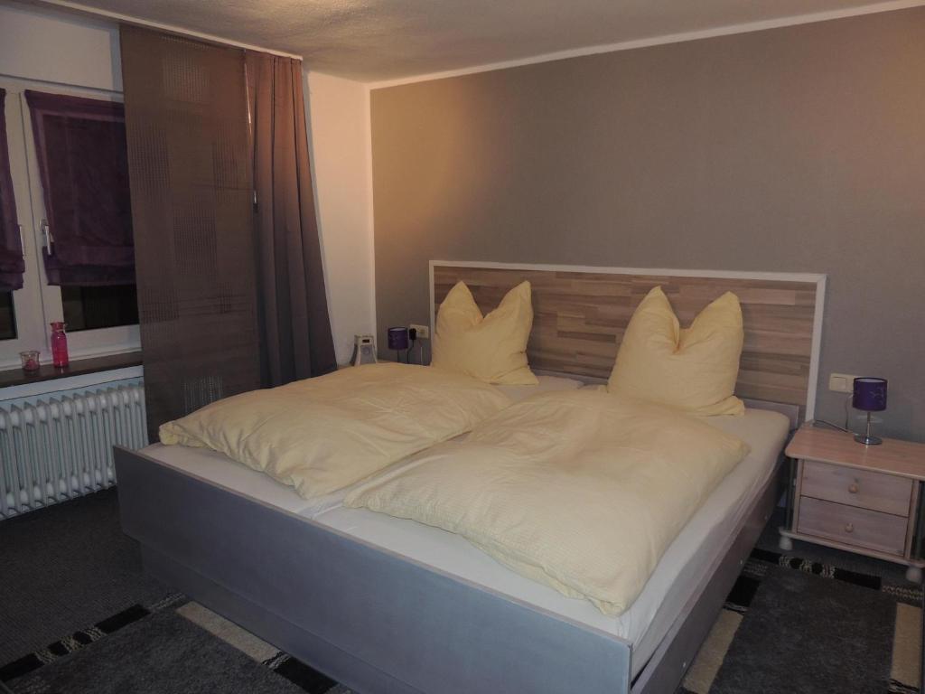 a bedroom with a bed with white sheets and pillows at Pension Neuenrade in Neuenrade