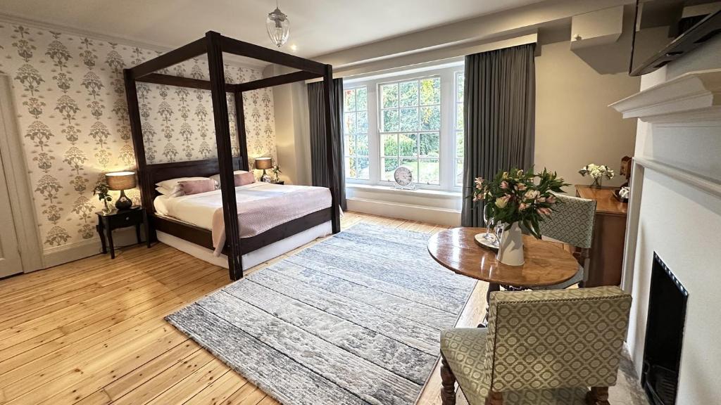 Holbrook Manor & Spa - OCEANA COLLECTION في وينكانتون: غرفة نوم مع سرير مظلة وطاولة وغرفة مع طاولة بلياردو