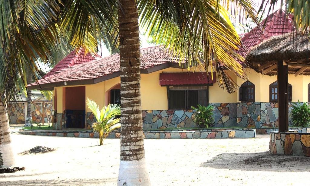 a house with a palm tree in front of it at Rent your own private beach bungalow in Ampeni