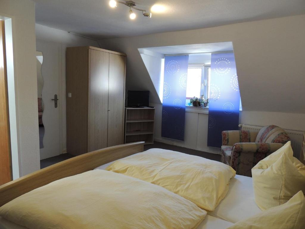 a bedroom with a bed and a chair and a window at Pension Neuenrade in Neuenrade