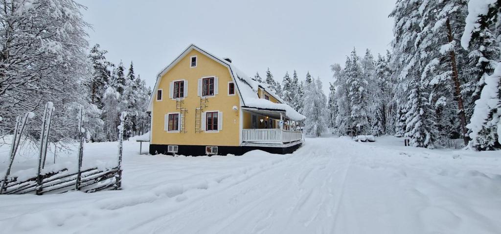 una casa amarilla en medio de una carretera cubierta de nieve en Horrmundsgården i Sälen, en Sälen