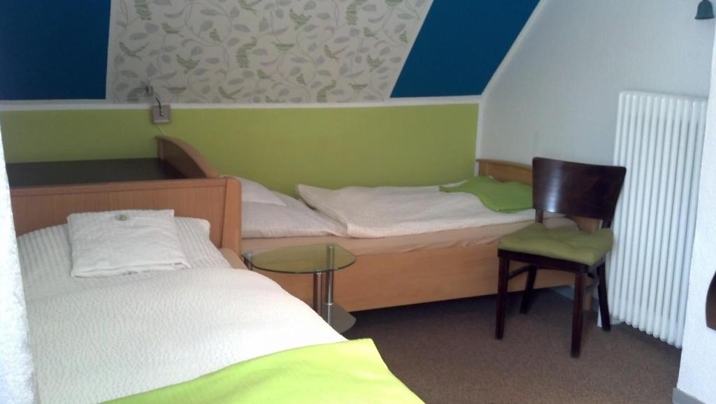 a room with two beds and a chair and a table at Pension Neuenrade in Neuenrade