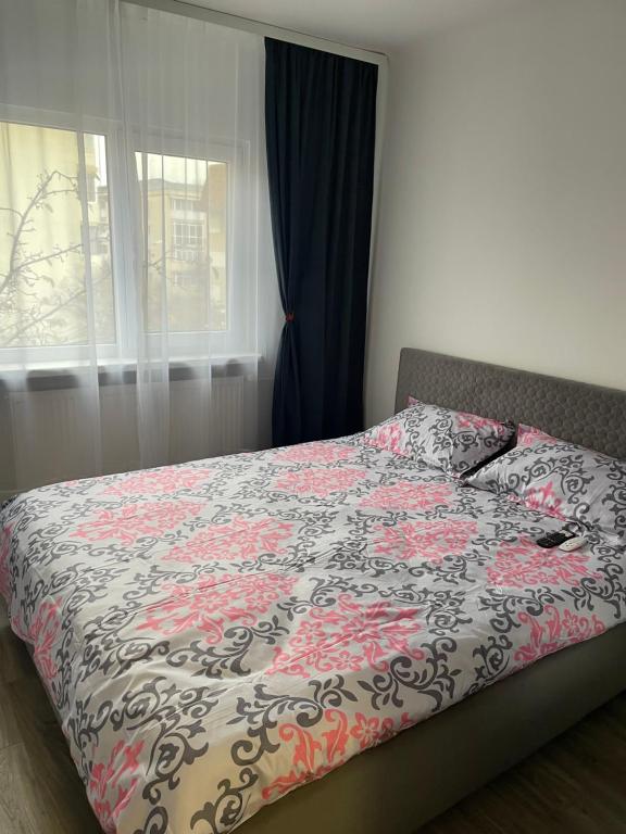 a bedroom with a bed with a flowered blanket and a window at TwinsHause in Craiova