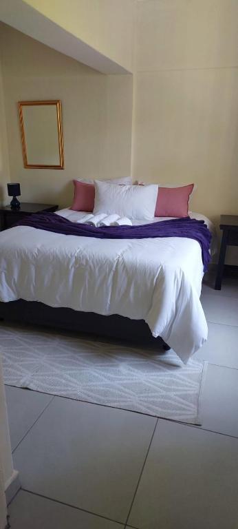 1 dormitorio con 1 cama con sábanas blancas y almohadas rojas en Khanyisa Accommodation Services, en KwaDukuza