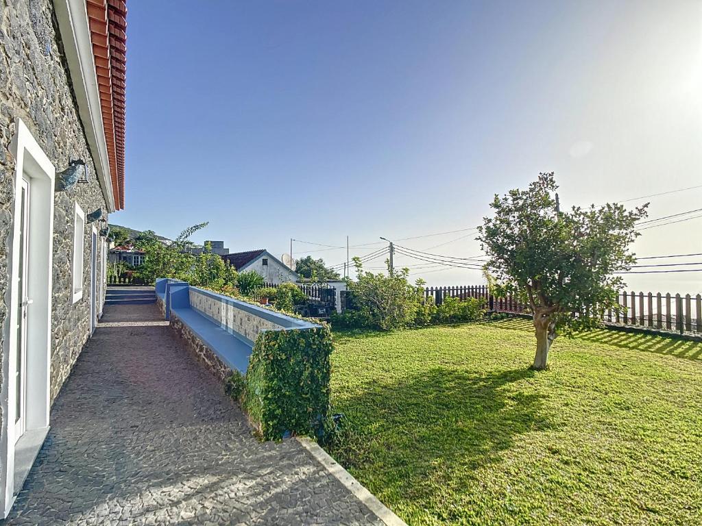 een achtertuin met een blauwe bank naast een huis bij Casa da Horta by Atlantic Holiday in Santa Cruz