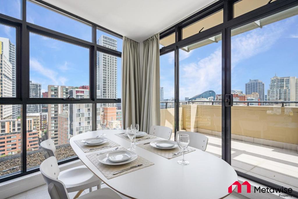 a white table and chairs in a room with windows at MetaWise Sydney CBD Haymarket Luxe 2Bed Penthouse Aqua in Sydney
