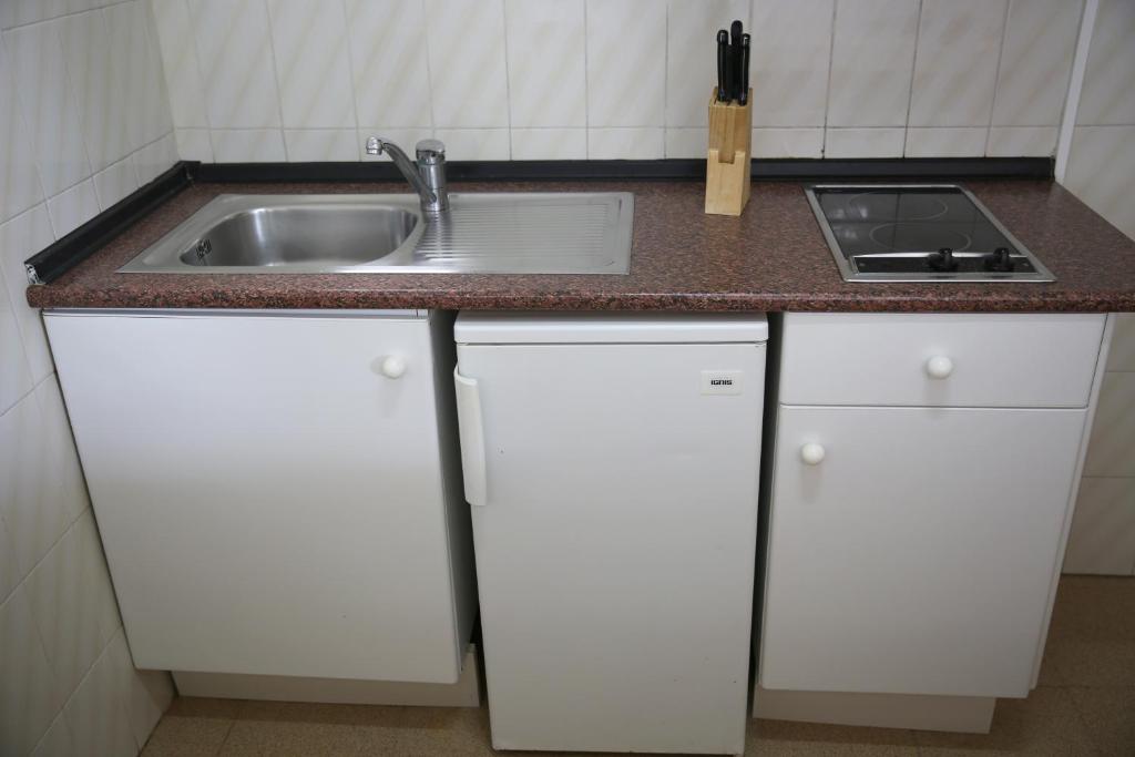 a kitchen with white cabinets and a sink at Apartamentos Mar y Sal in La Savina