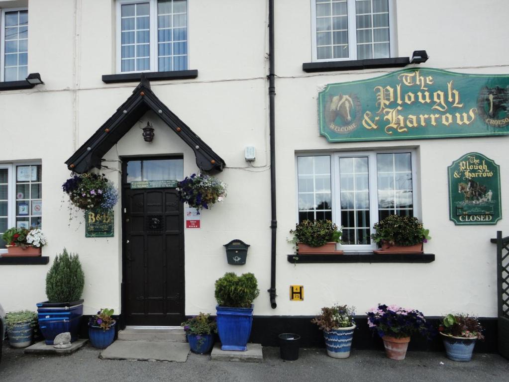 a white building with a black door and potted plants at Plough and Harrow in Brecon