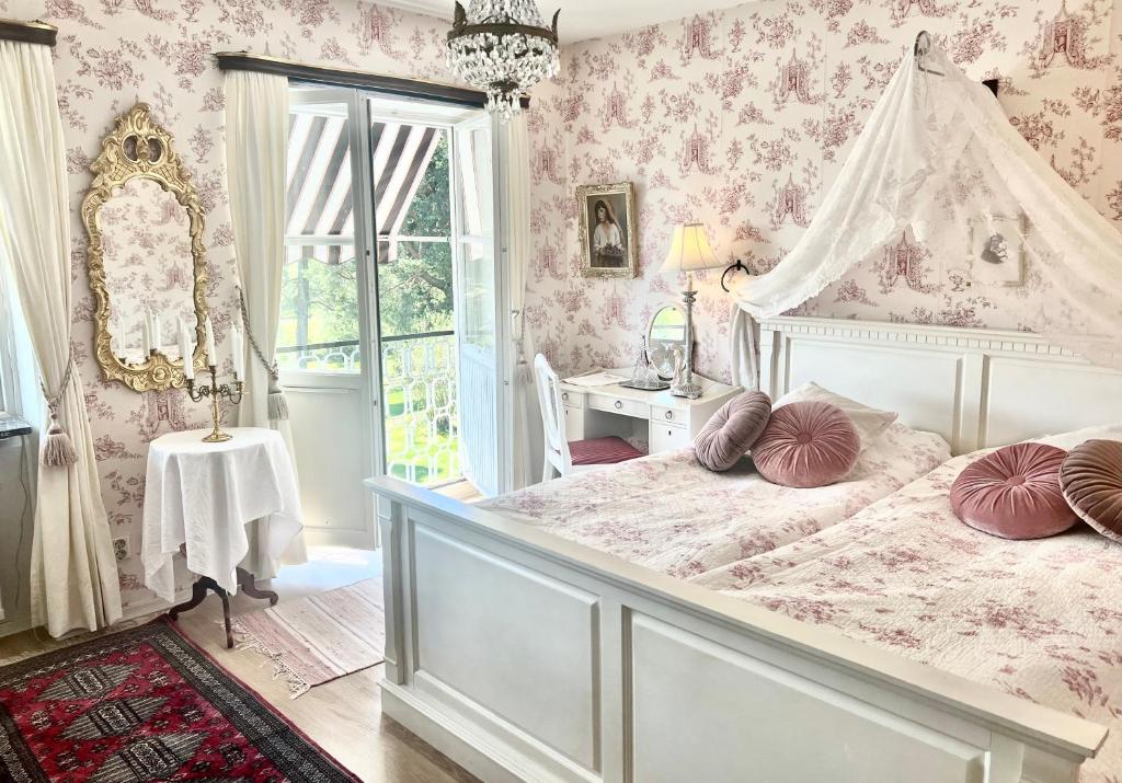 a bedroom with a white bed with pink wallpaper at Villa Billerud in Säffle