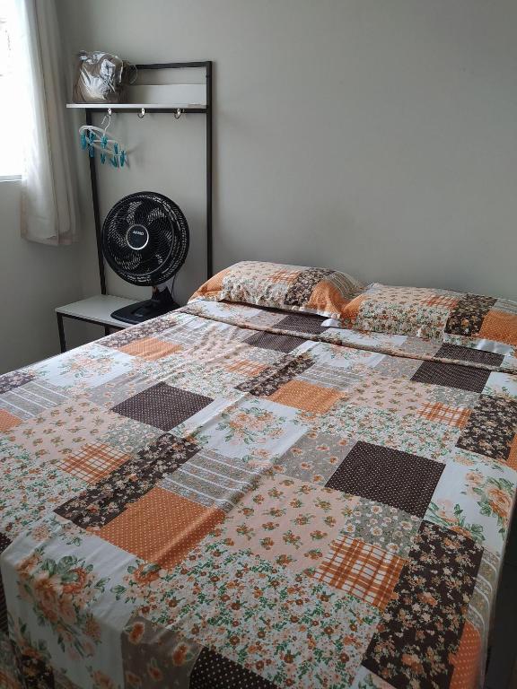 a quilt on a bed in a bedroom with a fan at KitNet Confort Garanhuns (101) in Garanhuns