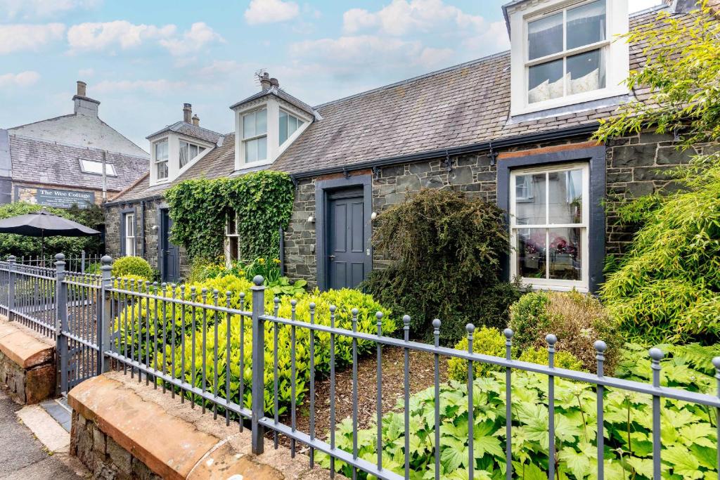 a stone house with a fence in front of it at Shepherdess Cottage in Moffat