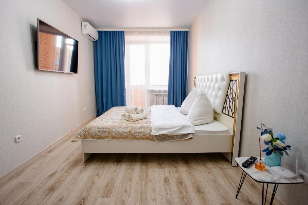a bedroom with a bed with blue curtains and a window at 1-ком Тобол Арена, Костанай Плаза, Allur auto, НИШ БЕРЕКЕ in Kostanay