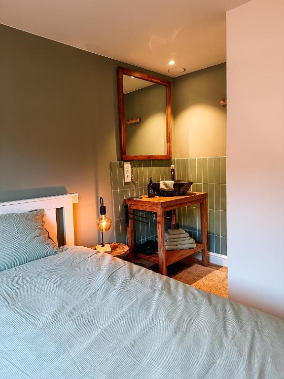 a bedroom with a bed and a table with a mirror at Vakantiehuis Maison Madeleine centrum Ieper in Ieper