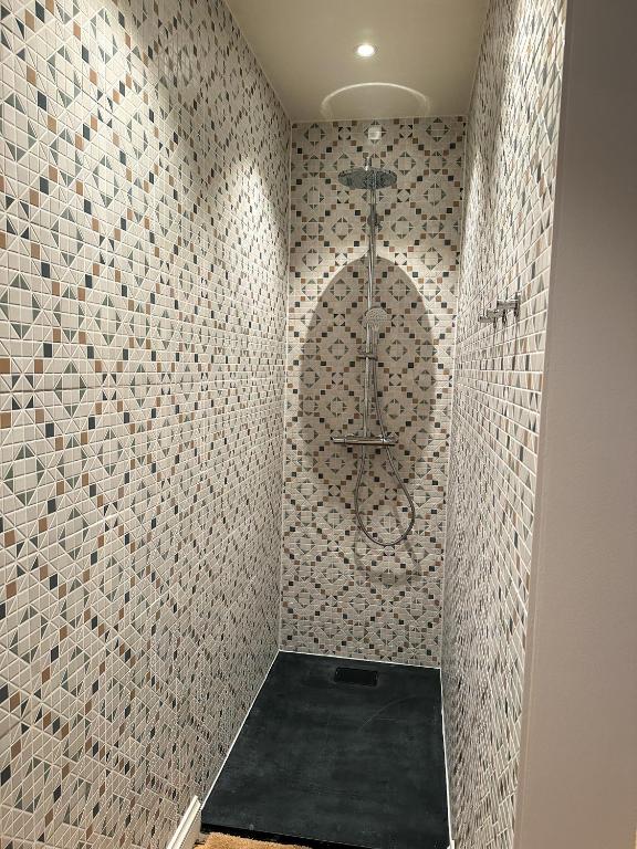 a shower in a bathroom with a tile wall at Vakantiehuis Maison Madeleine centrum Ieper in Ieper