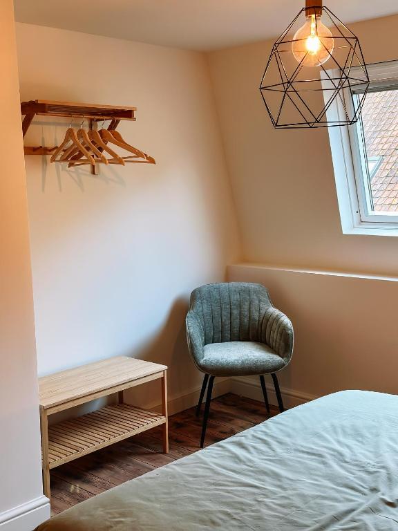 a bedroom with a chair and a table at Vakantiehuis Maison Madeleine centrum Ieper in Ieper