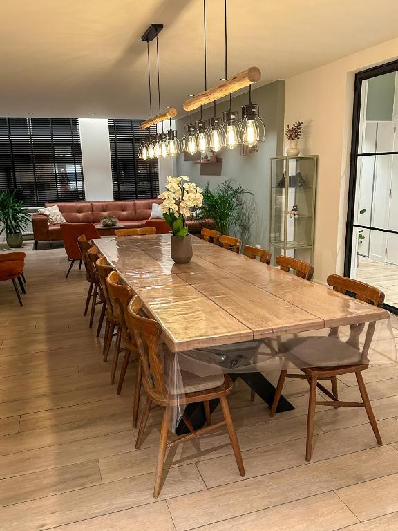 a dining room with a large wooden table and chairs at Vakantiehuis Maison Madeleine centrum Ieper in Ieper