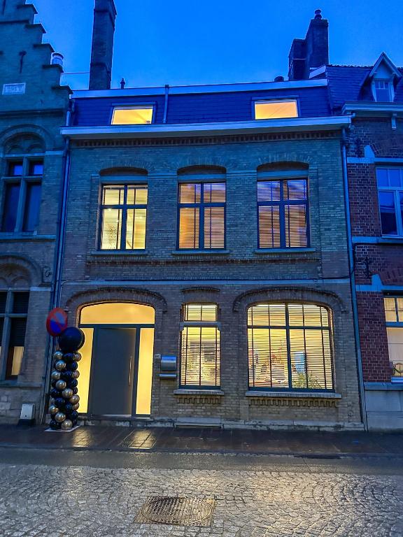 a brick building with lit windows on a street at Vakantiehuis Maison Madeleine centrum Ieper in Ieper