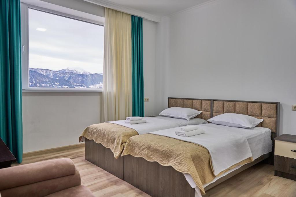 a bedroom with a large bed and a large window at Hotel Lile • სასტუმრო ლილე in Khulo