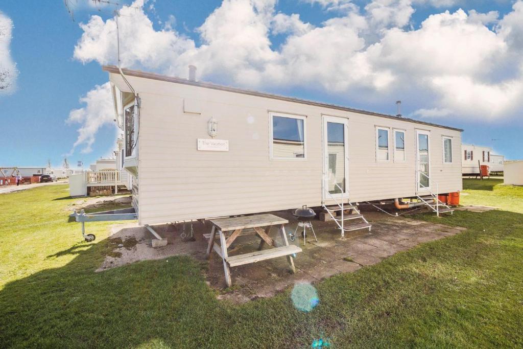 a white house with a picnic table and a bench at Spacious 8 Berth Caravan At Heacham Beach Holiday Park In Norfolk Ref 21027b in Heacham