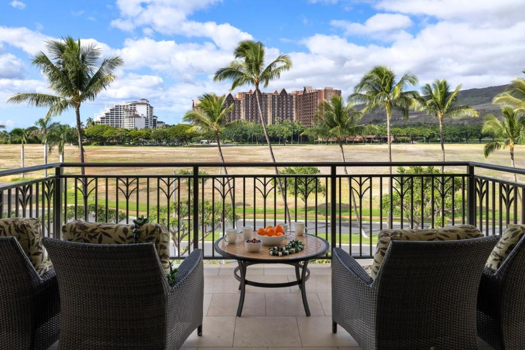 a balcony with a table and chairs and palm trees at Ko Olina Beach Villas O414 in Kapolei