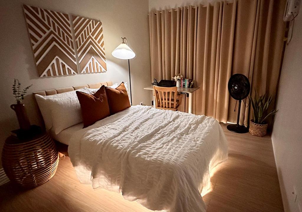 una camera da letto con un letto bianco con una lampada e un tavolo di 1618D at The Hive Residences a Taytay