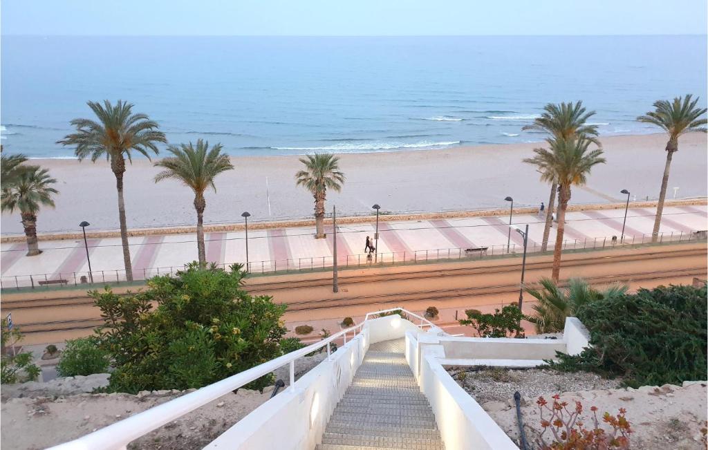 a stairway leading down to a beach with palm trees at Beautiful Apartment In El Campello With 2 Bedrooms, Wifi And Outdoor Swimming Pool in El Campello