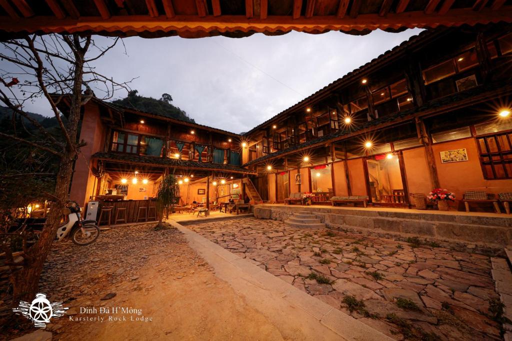 un edificio con una pasarela de piedra delante de él por la noche en Dinh Đá H'Mông - Karsterly Rock Lodge, en Dồng Văn