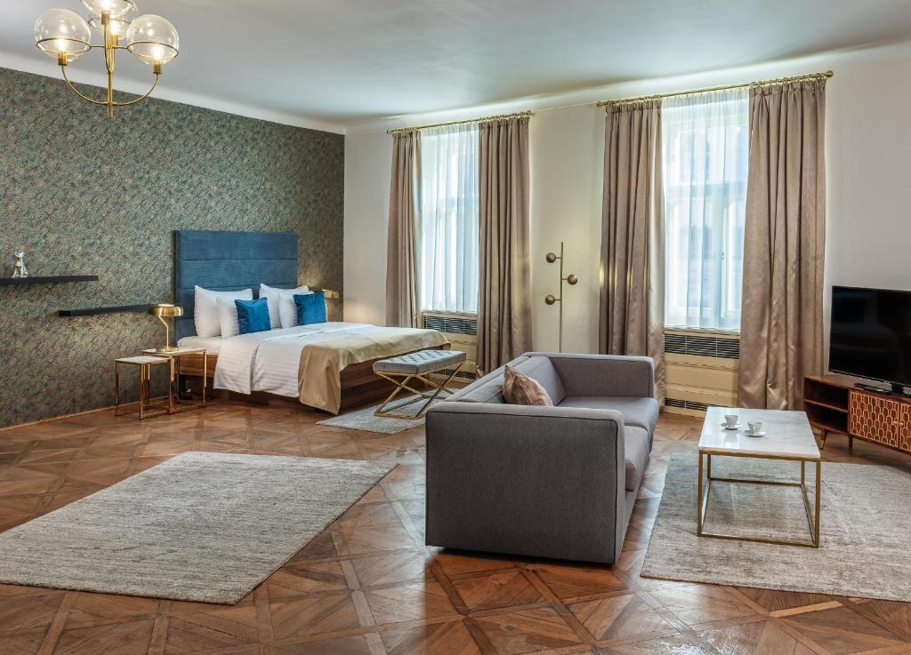 Golden Angel Suites by Adrez في براغ: غرفه فندقيه بسرير واريكه