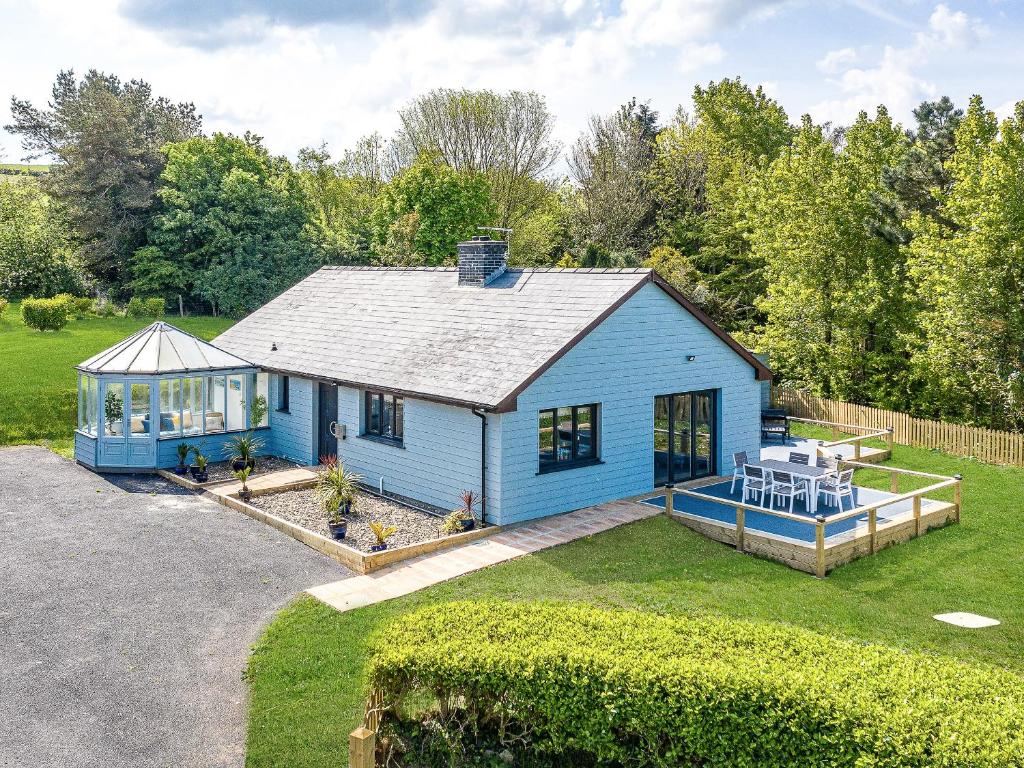 niebieski dom ze stołem i krzesłami na dziedzińcu w obiekcie Great Tree House w mieście Llangranog